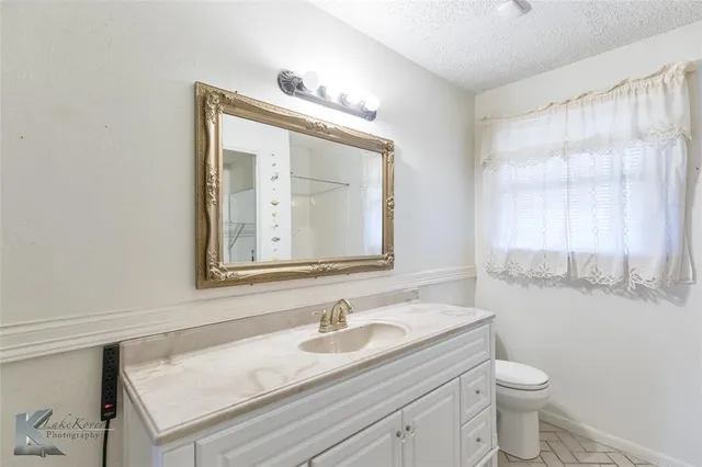 a bathroom with a granite countertop sink a toilet and a mirror