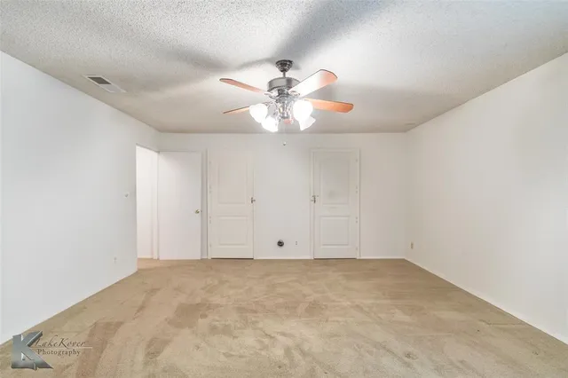 an empty room with a chandelier fan