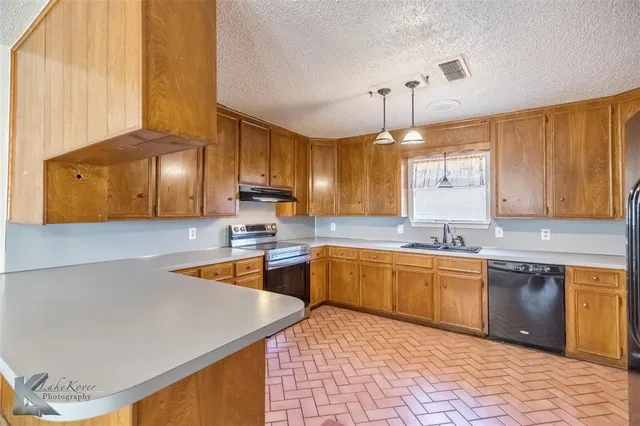 a kitchen with stainless steel appliances granite countertop a sink dishwasher and a stove with wooden cabinets