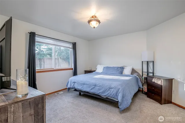 a bedroom with a bed and a flat tv screen on the dresser