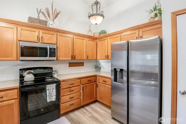 a kitchen with stainless steel appliances granite countertop a refrigerator a stove and a sink with wooden floor