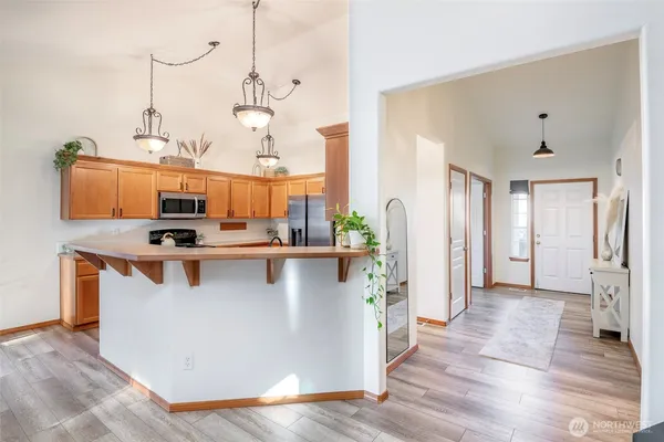 a kitchen with stainless steel appliances granite countertop a refrigerator a sink dishwasher a stove and white cabinets with wooden floor
