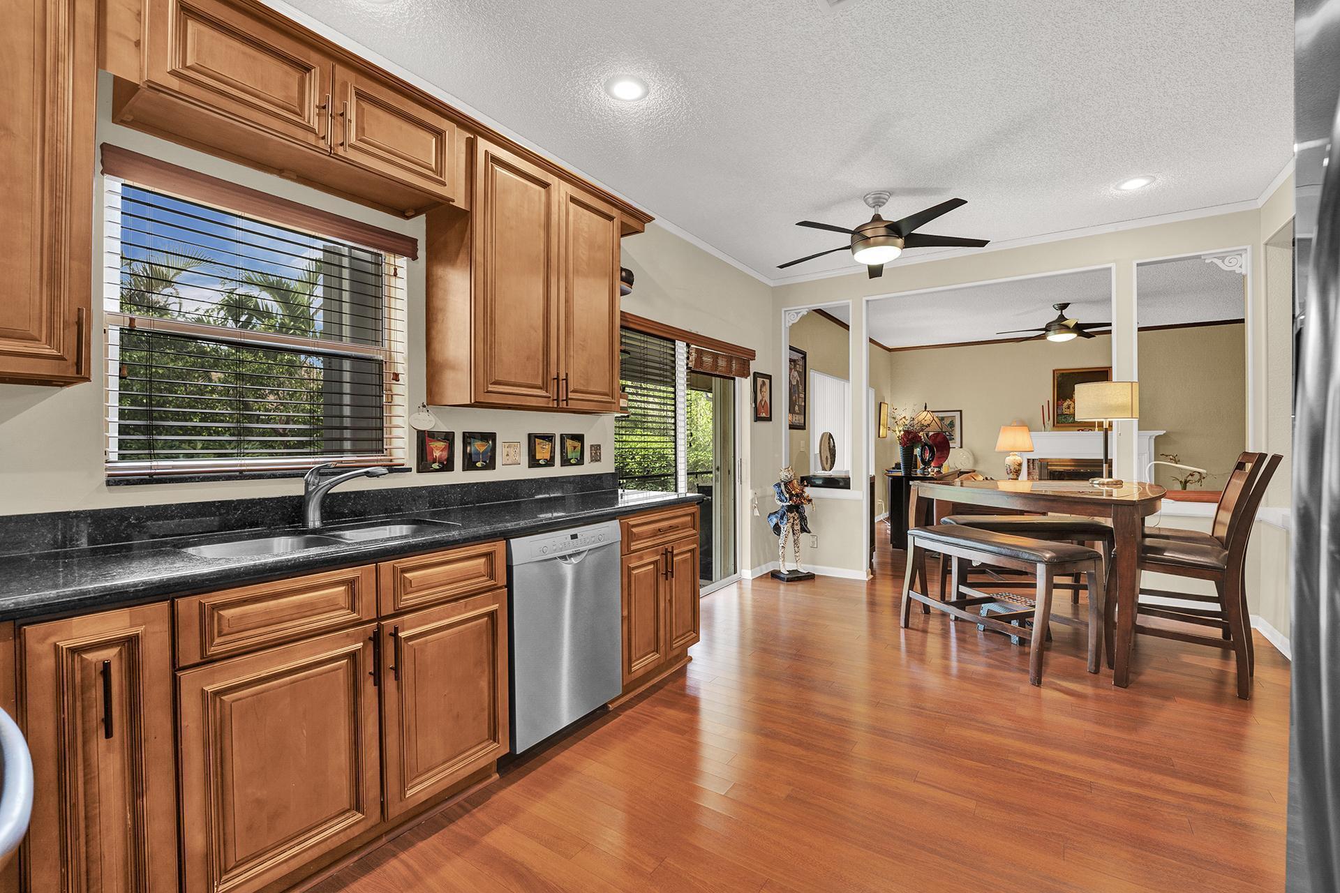 22211 Clocktower Way Boca Raton, FL 33428 - Photo 16 of 38 a open kitchen with granite countertop a dining table chairs refrigerator and wooden cabinets
