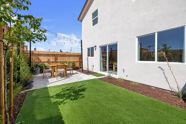 a view of a patio with table and chairs potted plants and large tree