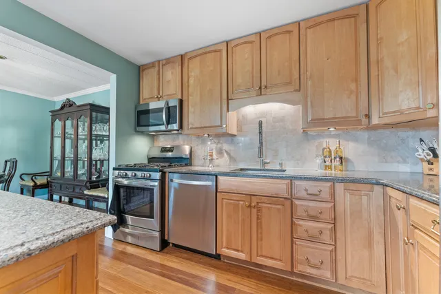 a kitchen with stainless steel appliances granite countertop a stove a sink dishwasher and microwave with wooden cabinets