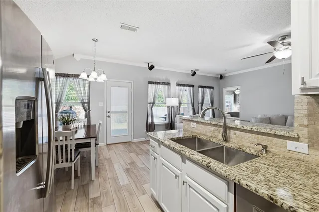 a kitchen with granite countertop a sink stove and refrigerator