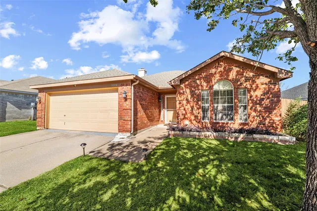 a view of a house with a small yard and a large tree