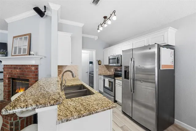 a kitchen with stainless steel appliances granite countertop a refrigerator a stove and a sink