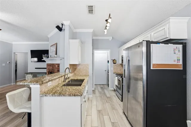 a kitchen with granite countertop kitchen island stainless steel appliances a sink stove and refrigerator