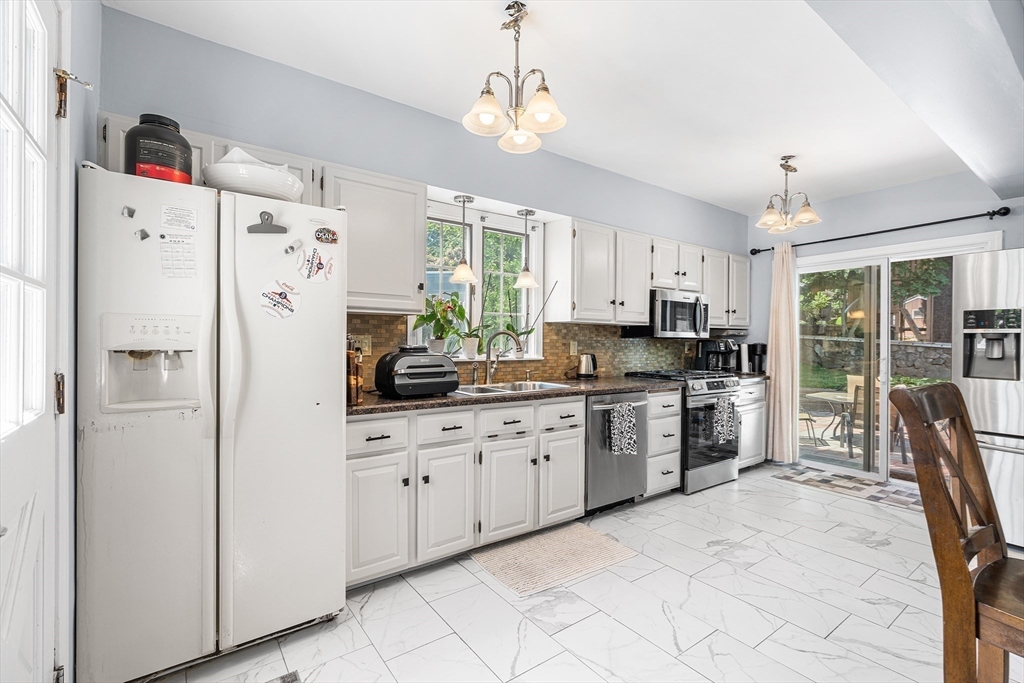 3 Fitz Road Peabody, MA 01960 - Photo 6 of 34 a kitchen with granite countertop a refrigerator a sink dishwasher a stove and a dining table with wooden floor