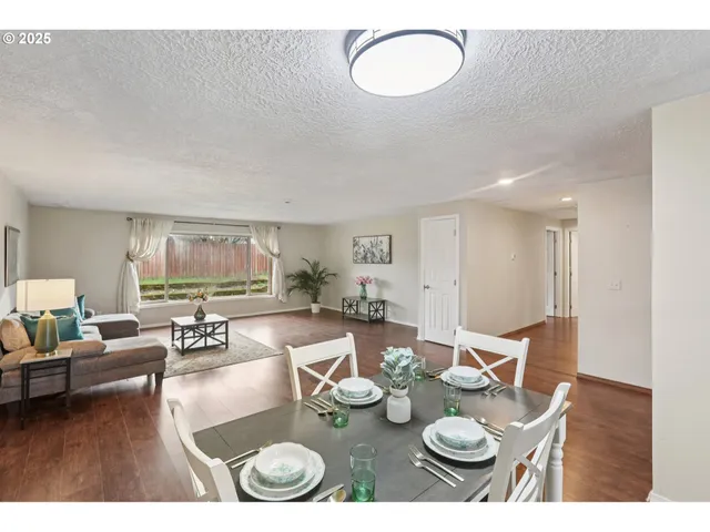 a view of a dining room and livingroom with furniture wooden floor a rug and a chandelier