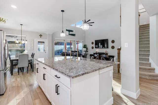 a kitchen with stainless steel appliances granite countertop a sink dishwasher and a dining table with wooden floor