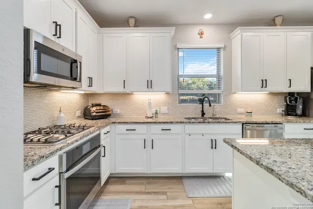 a kitchen with granite countertop cabinets stainless steel appliances and a sink