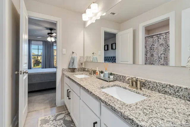 a bathroom with a granite countertop double vanity sink a mirror and shower