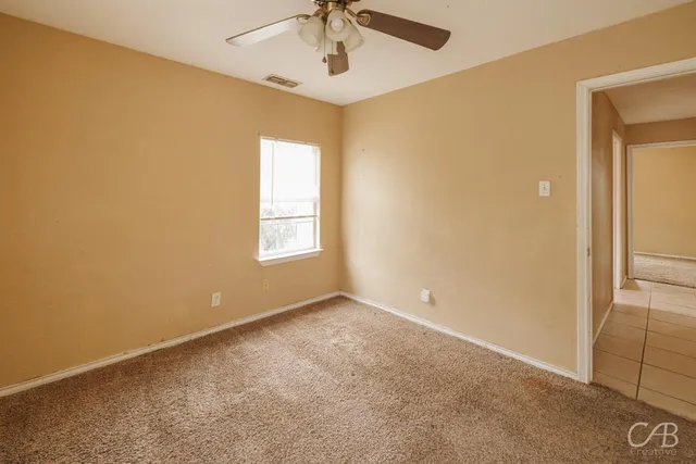 en empty room with windows and ceiling fan
