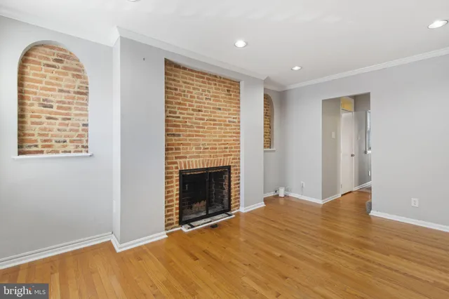 a view of an empty room with wooden floor fireplace and a window