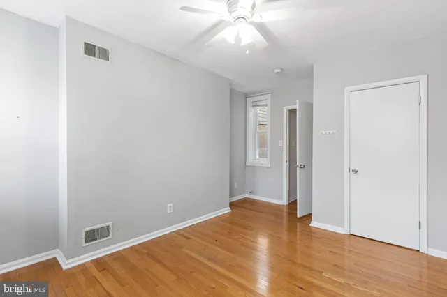 an empty room with wooden floor and fan