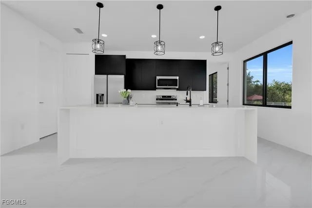 a view of kitchen with stainless steel appliances kitchen island refrigerator stove and microwave