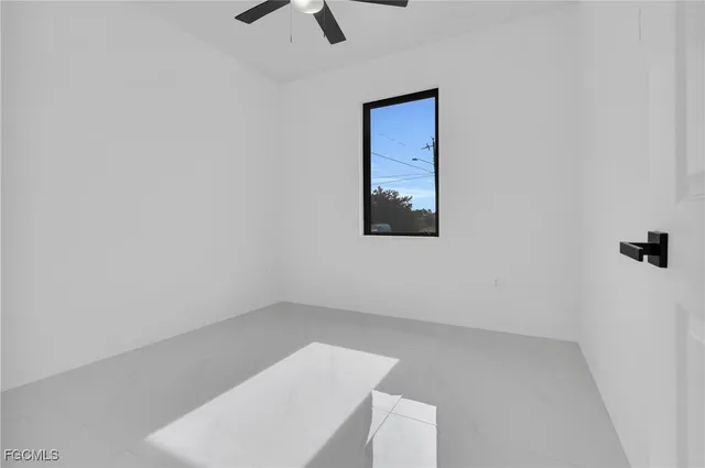 an empty room with a ceiling fan and window