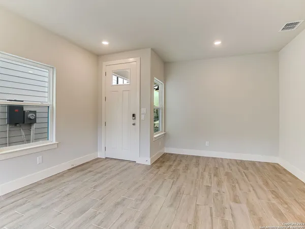 a view of an empty room with a window and wooden floor