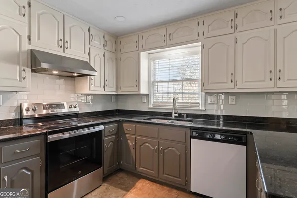 a kitchen with cabinets appliances a sink and a window