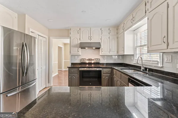 a kitchen with granite countertop a refrigerator stove and sink