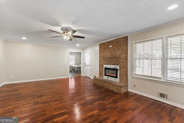 a view of a livingroom with a ceiling fan a fireplace and wooden floor