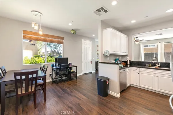 a kitchen with stainless steel appliances granite countertop wooden floor large window dining table and chairs