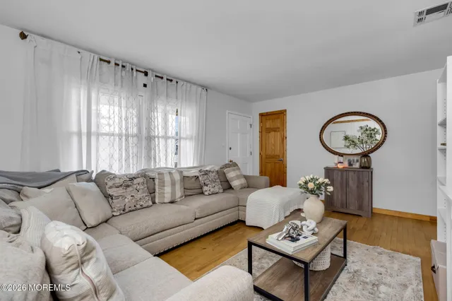 a living room with furniture a clock on wall and a window