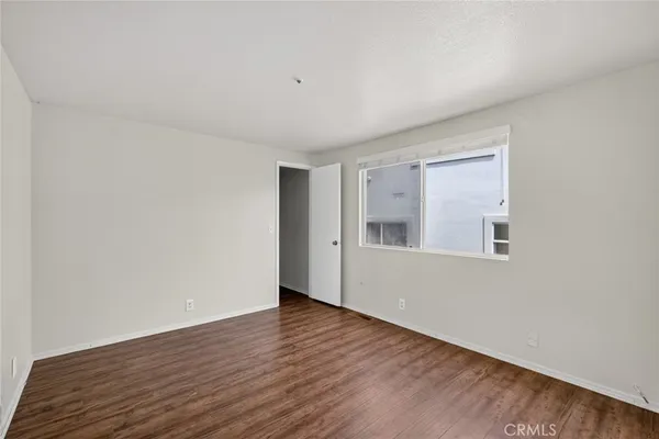 a view of an empty room with wooden floor and a bathroom