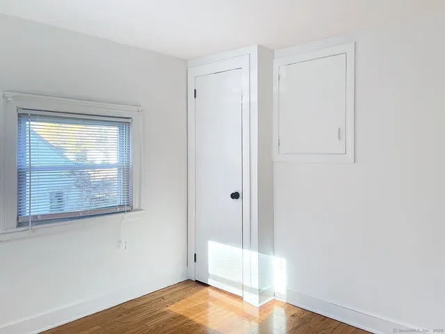 a view of a bedroom with wooden floor and a window