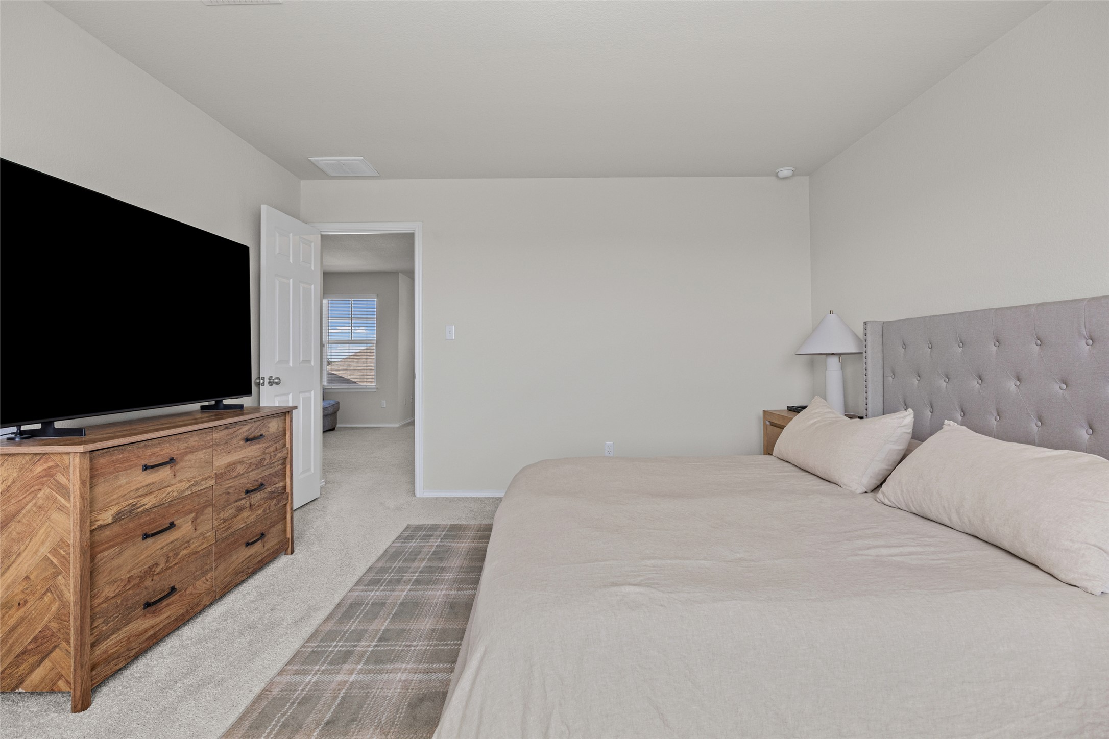 208 Orange Road Buda, TX 78610 - Photo 13 of 31 Well-lit and tranquil, this bedroom features soft carpeting and a clear view into an adjoining space.