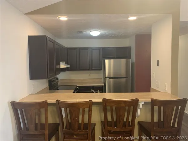 a kitchen with a dining table chairs cabinets and stainless steel appliances