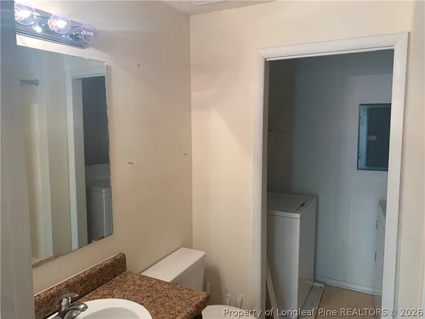 a bathroom with a granite countertop sink and a toilet
