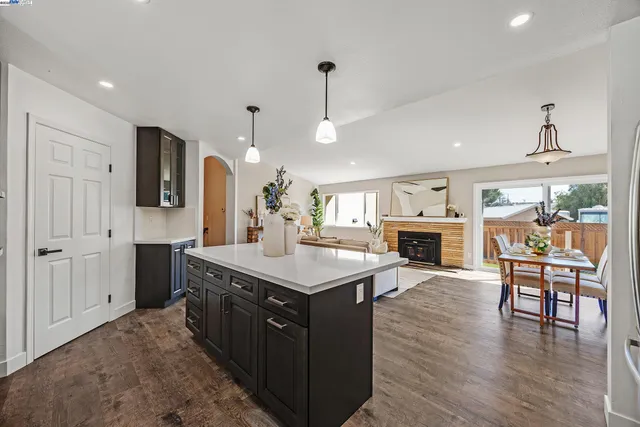 a kitchen with a stove a refrigerator a dining table and chairs with wooden floor