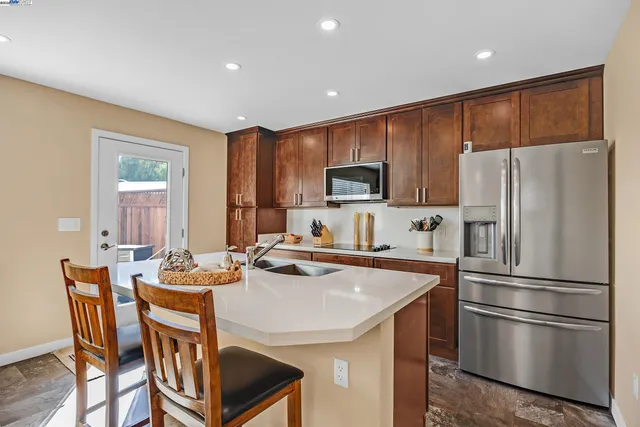 a kitchen with stainless steel appliances a refrigerator a stove a sink a dining table and chairs