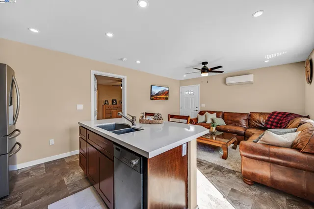 a living room with stainless steel appliances granite countertop furniture a sink a rug and a window