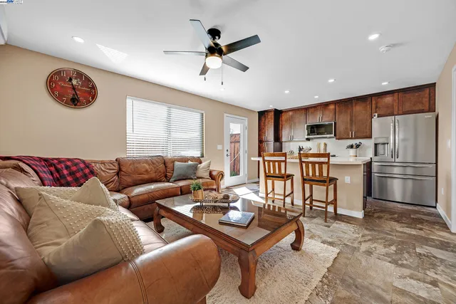 a living room with furniture kitchen area and stainless steel appliances