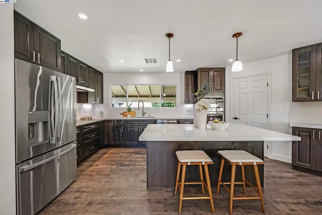 a kitchen with granite countertop a refrigerator and a stove top oven
