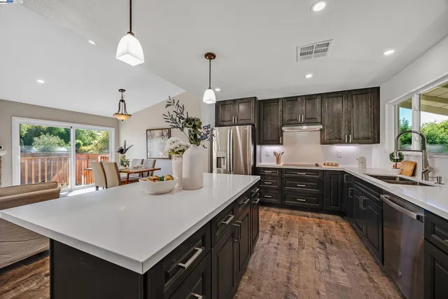 a kitchen with stainless steel appliances granite countertop a sink a stove and a refrigerator