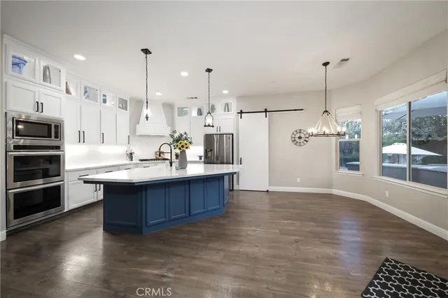 a large kitchen with stainless steel appliances a large counter top a stove and a wooden floors