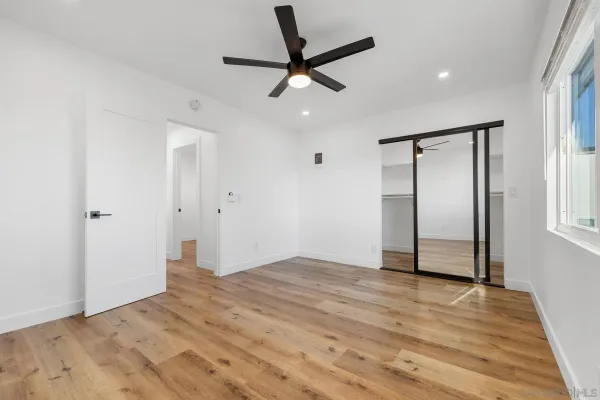 a view of empty room with wooden floor and fan