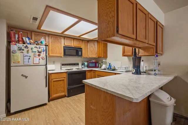 a kitchen with stainless steel appliances granite countertop a refrigerator a sink dishwasher and a stove with wooden cabinets