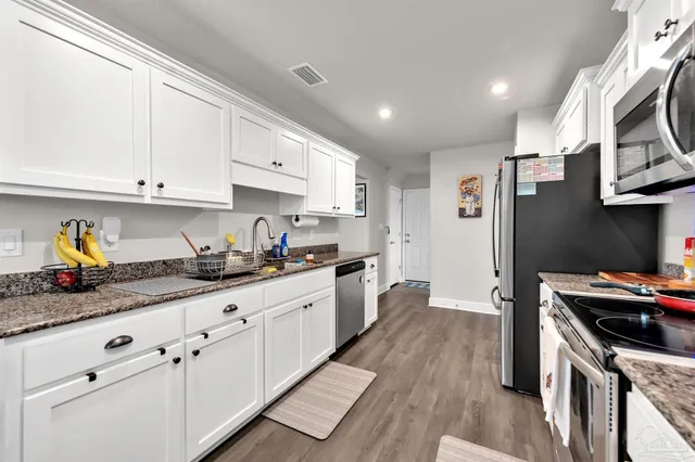 a kitchen with granite countertop a sink stainless steel appliances and cabinets