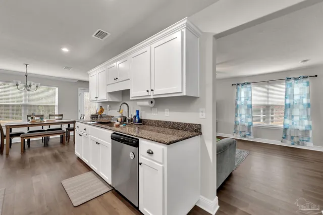 a kitchen with stainless steel appliances granite countertop a stove a sink dishwasher and a refrigerator with wooden floor