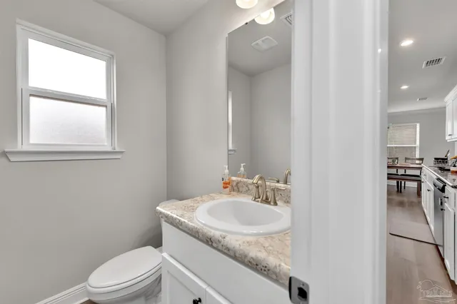 a bathroom with a granite countertop sink a toilet and a window