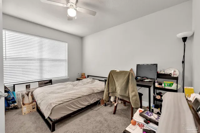 a bedroom with a bed a computer on a desk and a printer on the dresser