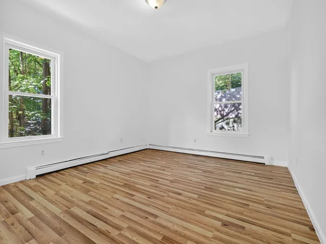 a view of an empty room with a window and wooden floor