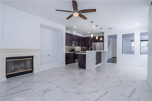 an empty room with a fireplace and a ceiling fan