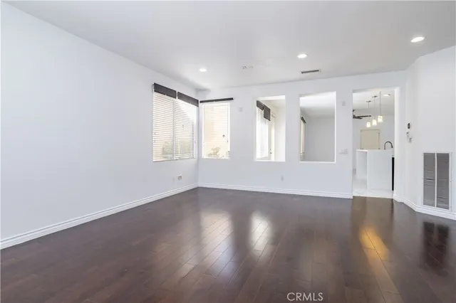 a view of an empty room with wooden floor and staircase